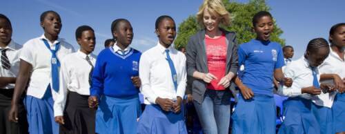 actor Charlize Theron dancing with a group of young students